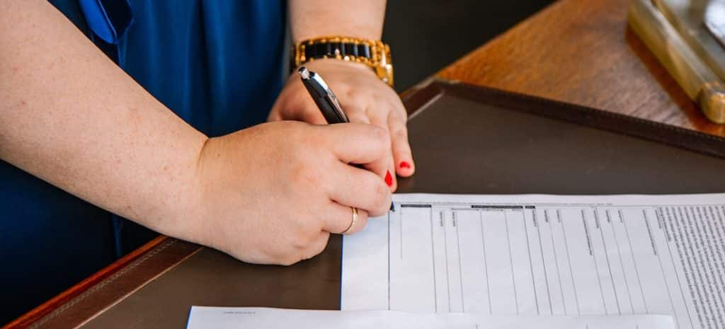 An image of someone signing paperwork.