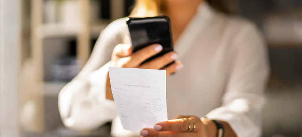 Woman Scanning Receipt for Taxes Using Mobile Phone Woman Scanning Receipt for Taxes Using Mobile Phone