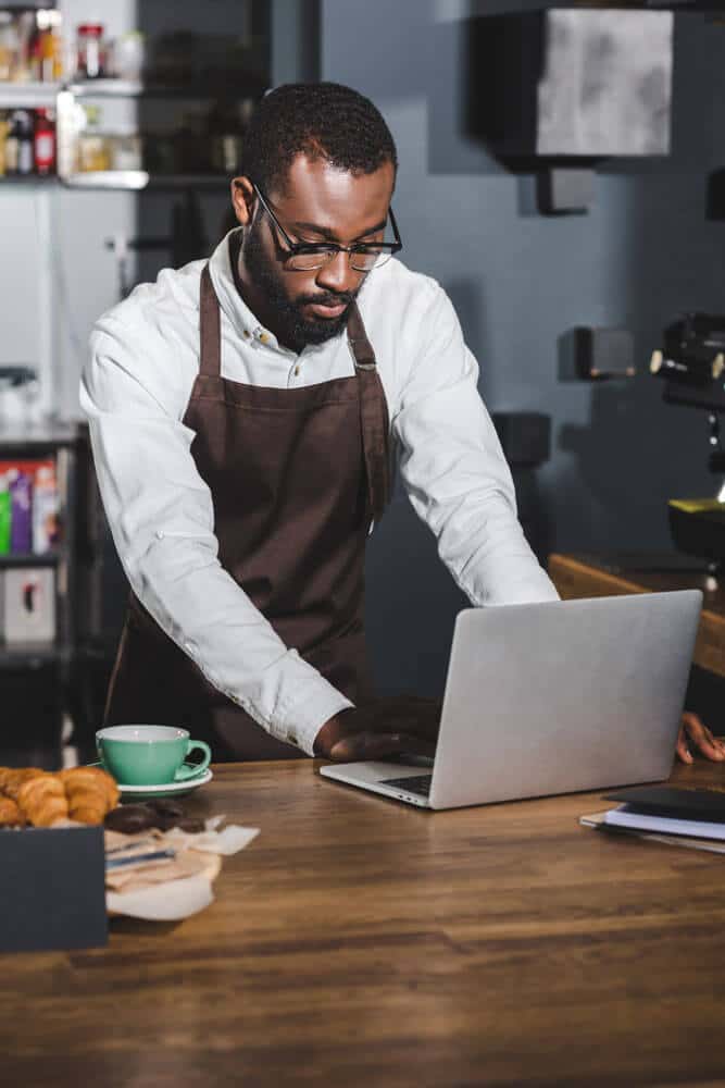 Coffee shop business owner using a laptop. Coffee shop business owner using a laptop.
