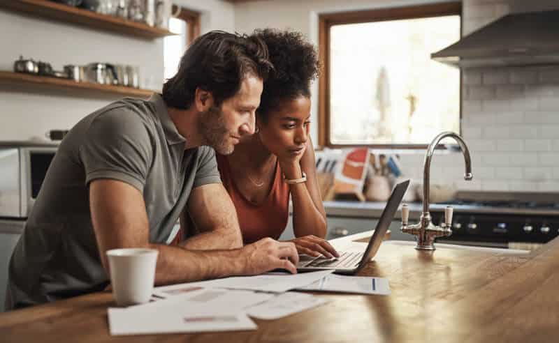 Couple looking at their laptop in the kitchen. 