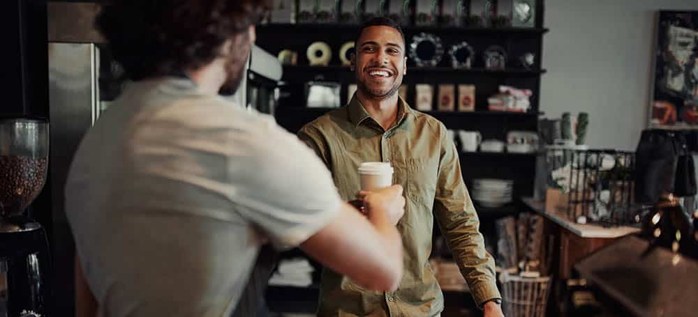 Customer buying takeaway coffee from modern cafe house business owner
